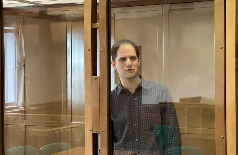  Wall Street Journal reporter Evan Gershkovich, who is in custody on espionage charges, stands behind a glass wall of an enclosure for defendants as he attends a court hearing to consider extending his detention in Moscow, Russia, March 26, 2024. (credit: Moscow City Court's Press Office/Handout via REUTERS)