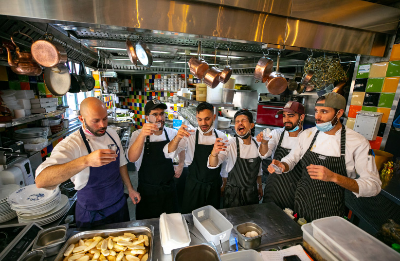  The chef and his staff hold a glass of arak to celebrate the reopenning as they  cook prior to the reopenning of the Machneyuda restaurant on March 07, 2021 in Jerusalem. (credit: OLIVIER FITOUSSI/FLASH90)