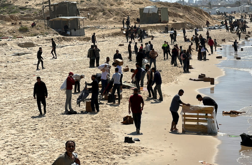 Palestinos se reúnen en una playa mientras recogen ayuda lanzada desde un avión, en medio del actual conflicto entre Israel y Hamás, en el norte de la Franja de Gaza, 25 de marzo de 2024. (credit: REUTERS/STRINGER)