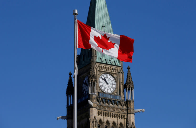  Una bandera canadiense ondea frente a la Torre de la Paz en la Colina del Parlamento en Ottawa, Ontario, Canadá, 22 de marzo de 2017. (credit: CHRIS WATTIE/REUTERS)