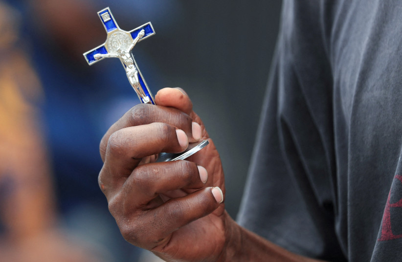 A person holds a crucifix outside a Catholic church in Harare, Zimbabwe March 29, 2024. (credit: PHILIMON BULAWAYO/REUTERS)