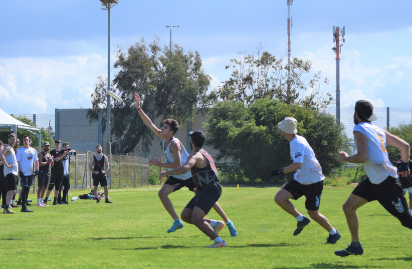 Halell Romano of Jerusalem Syndrome (L) reaches for a pass in front of his defender – and coach – Yaron Katzir, with teammates David Ross (R) and captain Ehud Dahan rushing to help, and Gidon Hazony (L) and Aryeh Lev Mason watching from the sideline.  (credit: Ayelet Ben Zion, IFDA)