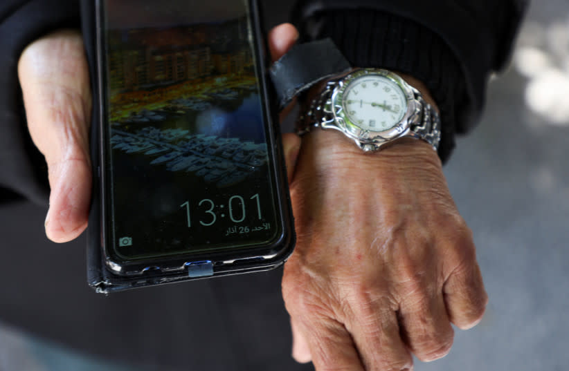 Mohamed al-Arab, musulmán libanés, muestra las diferentes horas en su reloj y teléfono móvil, en medio de una disputa entre autoridades políticas y religiosas sobre la decisión de ampliar el horario de invierno, en Beirut, Líbano, 26 de marzo de 2023. (credit: REUTERS/MOHAMED AZAKIR)