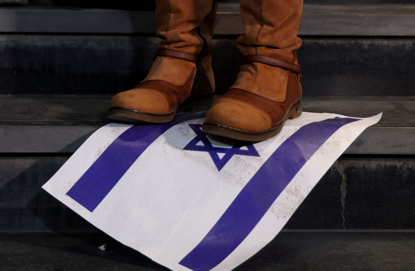 A person steps on a placard depicting an Israeli flag as demonstrators protest against Israel and in support of Palestinians, during a demonstration to mark 100 days since the start of the ongoing conflict between Israel and the Palestinian Islamist group Hamas, in front of the Egypt Journalists Syn (credit: AMR ABDALLAH DALSH / REUTERS)