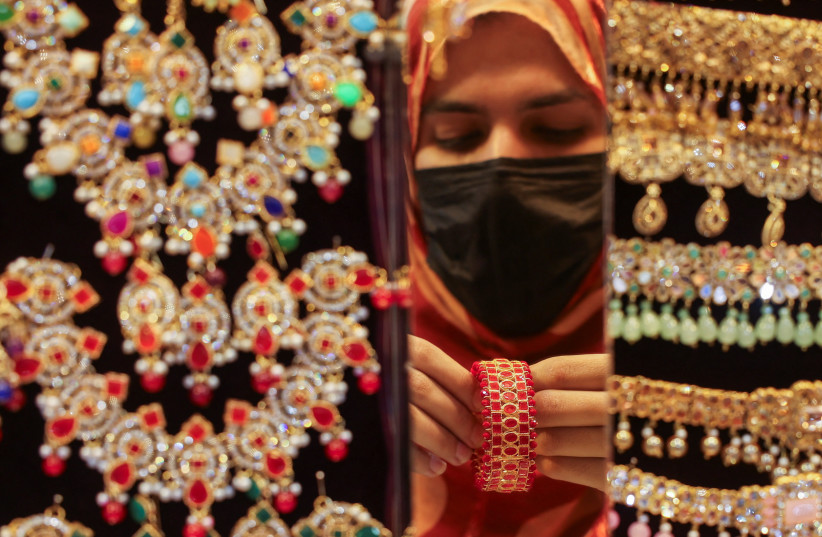  A woman is reflected in a mirror as she buys artificial jewelry from a shop ahead of the Eid al-Fitr celebrations in Peshawar, Pakistan April 8, 2024. (credit: REUTERS/FAYAZ AZIZ)