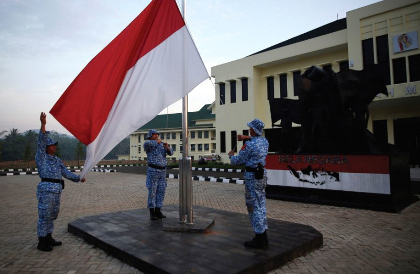  PARTICIPANTES IZAN una bandera indonesia en un centro de formación de Rumpin, Indonesia, el pasado mes de junio. (credit: REUTERS)