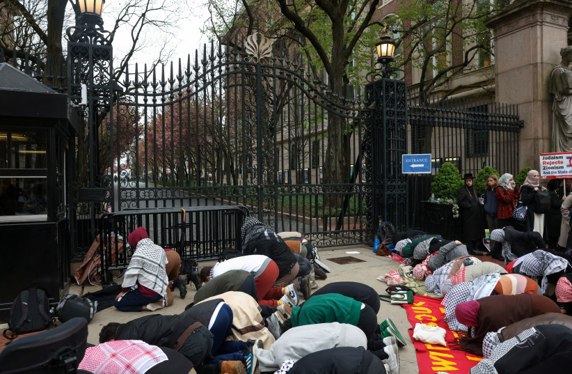 Demonstrators pray outside an entrance to the Columbia University campus as they protest in solidarity with Pro-Palestinian organizers, amid the ongoing conflict between Israel and the Palestinian Islamist group Hamas, in New York City, US, April 18, 2024. (credit: REUTERS/CAITLIN OCHS)