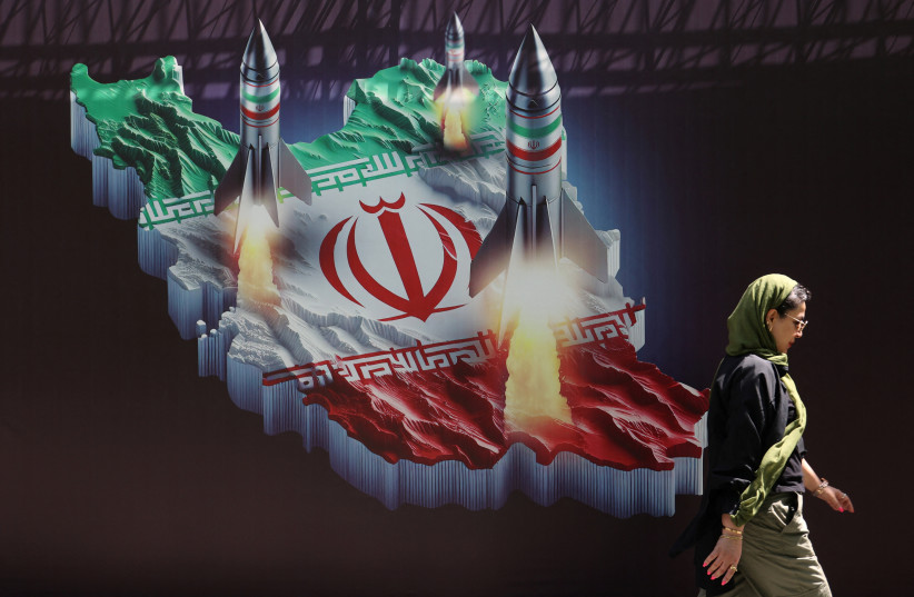  An Iranian woman walks past an anti-Israel banner with a picture of Iranian missiles on a street in Tehran, Iran April 19, 2024. (credit: MAJID ASGARIPOUR/WANA (WEST ASIA NEWS AGENCY) VIA REUTERS)