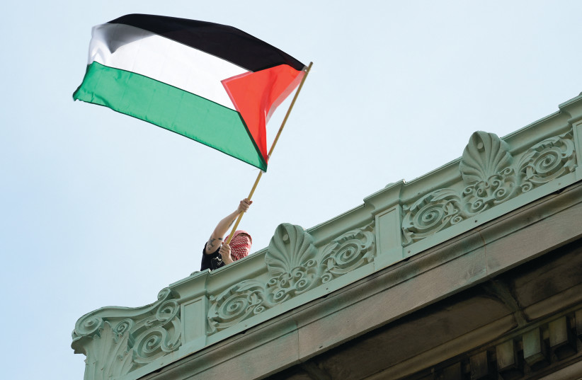 A STUDENT protester waves a Palestinian flag above Hamilton Hall on the campus of Columbia University in New York City on Tuesday.  (credit: MARY ALTAFFER/REUTERS)