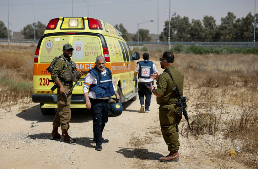 An Israeli medic walks near soldiers and an ambulance after Hamas claimed responsibility for an attack on Kerem Shalom crossing, May 5, 2024. (credit: REUTERS/AMIR COHEN)