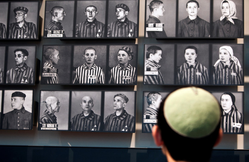 A visitor looks at pictures of Holocaust victims at Yad Vashem's Holocaust History Museum in Jerusalem (credit: REUTERS/NIR ELIAS)