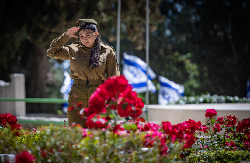  Israeli soldiers place Israeli flags on graves of Israeli soldiers during the flag laying ceremony in Mount Herzl Military Cemetery in Jerusalem, on May 8, 2024. (credit: YONATAN SINDEL/FLASH90)