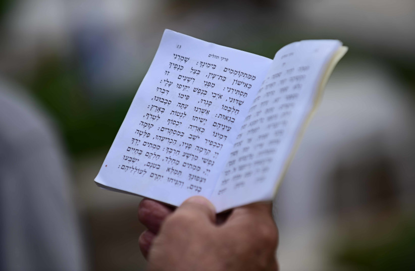 Un judío sostiene Tehillim, el libro de los Salmos, buscando consuelo en la oración el Día de los Caídos en Tel Aviv (crédito: TOMER NEUBERG/FLASH90)
