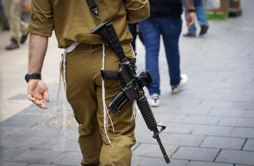 An IDF soldier is seen wearing a Jewish tzitzit while carrying a weapon in Jerusalem, May 13, 2024 (credit: MARC ISRAEL SELLEM)