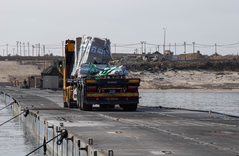 Trucks deliver humanitarian aid over a temporary pier on the Gaza coast, May 18, 2024 (credit: US ARMY CENTRAL/HANDOUT VIA REUTERS)