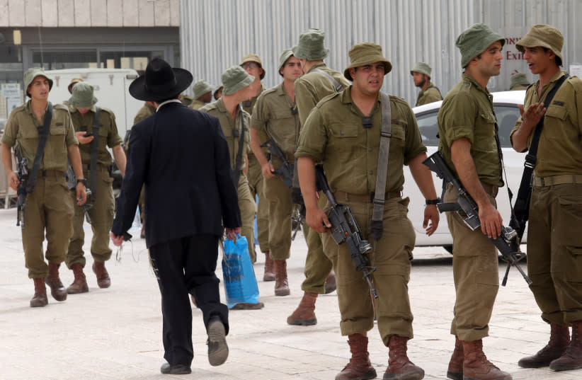  Un hombre ultraortodoxo pasa junto a un grupo de soldados israelíes en la Ciudad Vieja de Jerusalén durante la festividad judía de Rosh Hashana, el Año Nuevo judío, el 14 de septiembre de 2015. (credit: NATI SHOHAT/FLASH90)