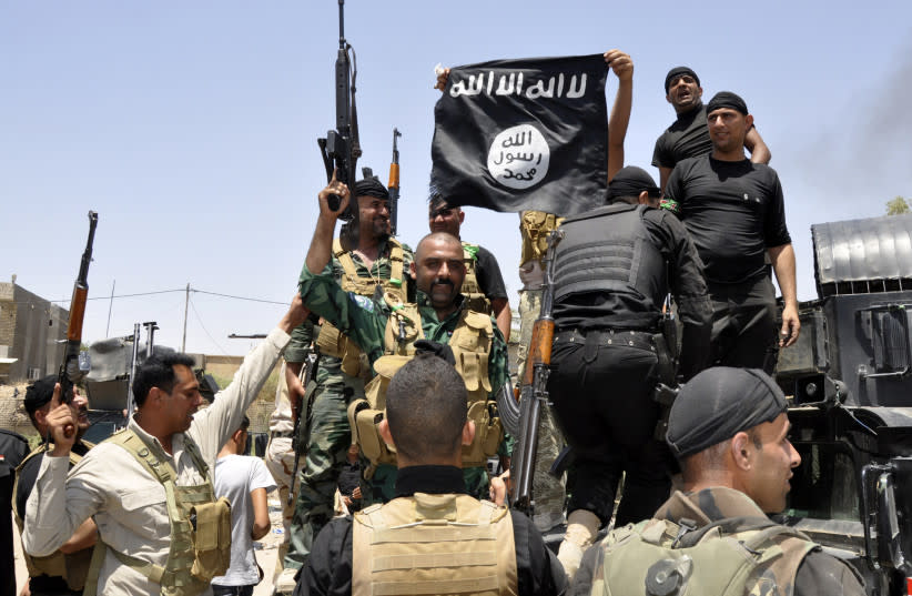   Fuerzas de seguridad iraquíes arrancan una bandera perteneciente al grupo militante suní Estado Islámico de Irak y el Levante (ISIL) durante una patrulla en la ciudad de Dalli Abbas, en la provincia de Diyala, 30 de junio de 2014. (credit: REUTERS/STRINGER)