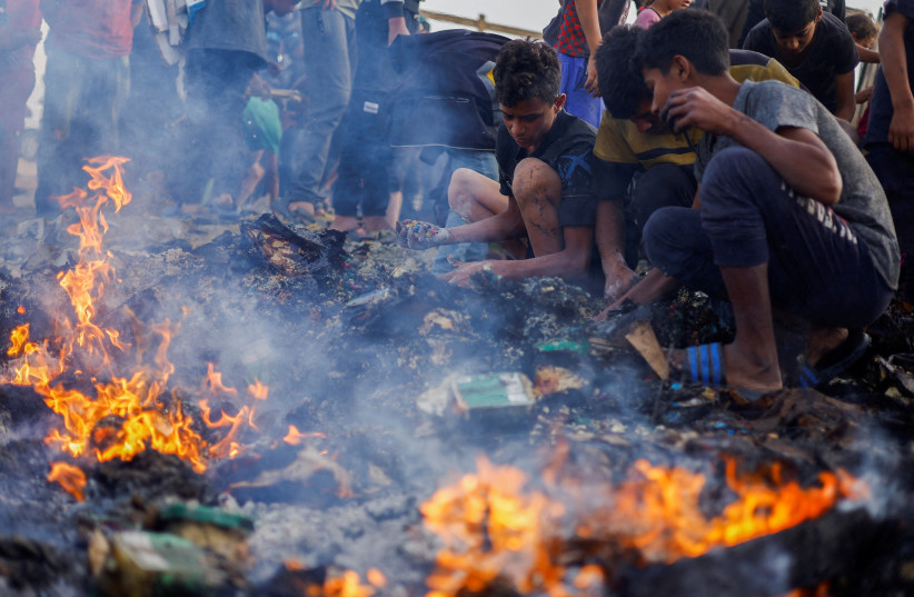 Palestinians search for food among burnt debris in the aftermath of an Israeli strike on an area designated for displaced people, in Rafah in the southern Gaza Strip, May 27, 2024. (credit: MOHAMMED SALEM/REUTERS)