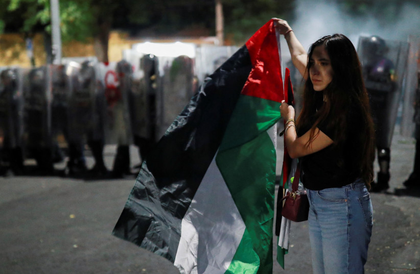  A protester holds up a Palestinian flag as riot police stand guard near the Israel Embassy during a demonstration in support of Palestinians, amid the ongoing conflict between Israel and Hamas, in Mexico City, Mexico May 28, 2024. (credit: REUTERS/HENRY ROMERO)