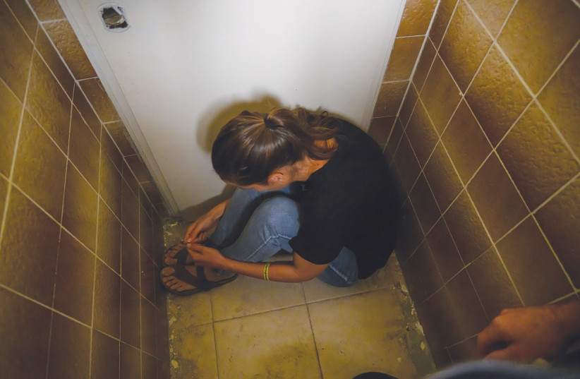  KIBBUTZ BE’ERI nurse Nirit Hunwald reenacts sitting on the floor in a bathroom stall. (credit: FLASH90)