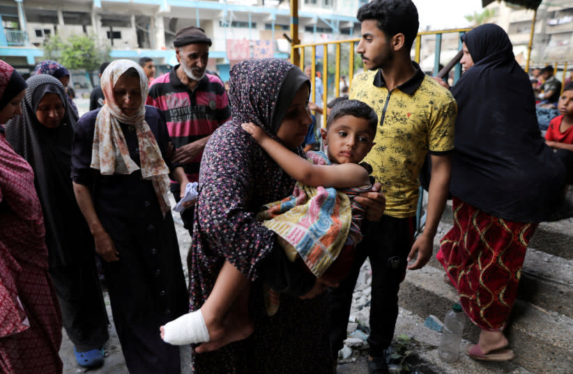 Una mujer lleva a un niño en el lugar de un ataque israelí contra una escuela de la UNRWA que acoge a personas desplazadas, en medio del conflicto entre Israel y Hamás, en el campo de refugiados de Nuseirat, en el centro de la Franja de Gaza, el 6 de junio de 2024.