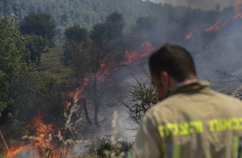  Israeli firefighters try to extinguish a fire after missiles launched from Lebanon hit open areas near the northern Israeli city of Safed, on June 12, 2024. (credit: MICHAEL GILADI/FLASH90)