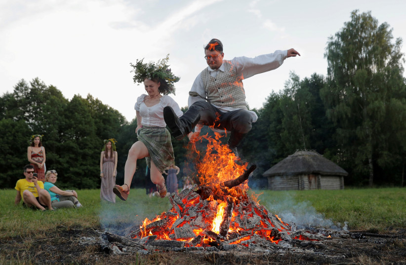  People jump over a campfire as they take part in the Ivan Kupala festival in Belarusian state museum of folk architecture and rural lifestyle near the village Aziarco, Belarus, July 4, 2020. (credit: REUTERS/VASILY FEDOSENKO)