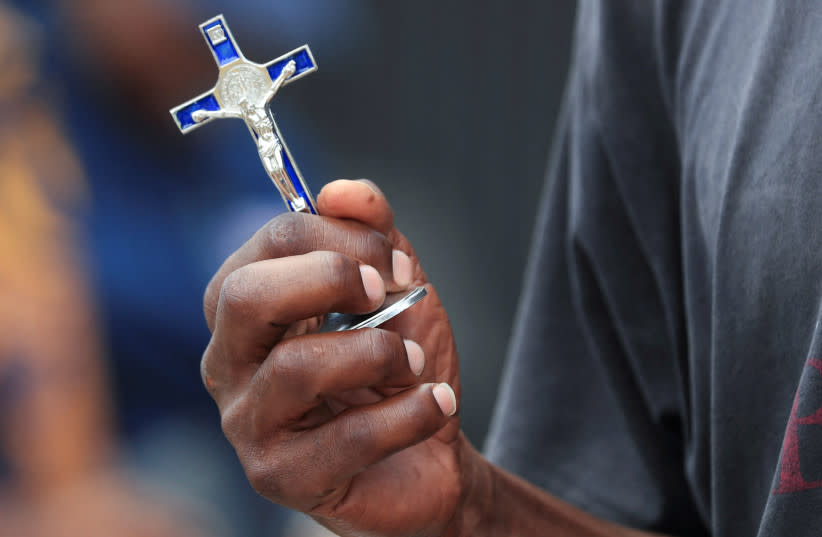  Una persona sostiene un crucifijo en el exterior de una iglesia católica en Harare, Zimbabue, 29 de marzo de 2024.  (credit: PHILIMON BULAWAYO/REUTERS)