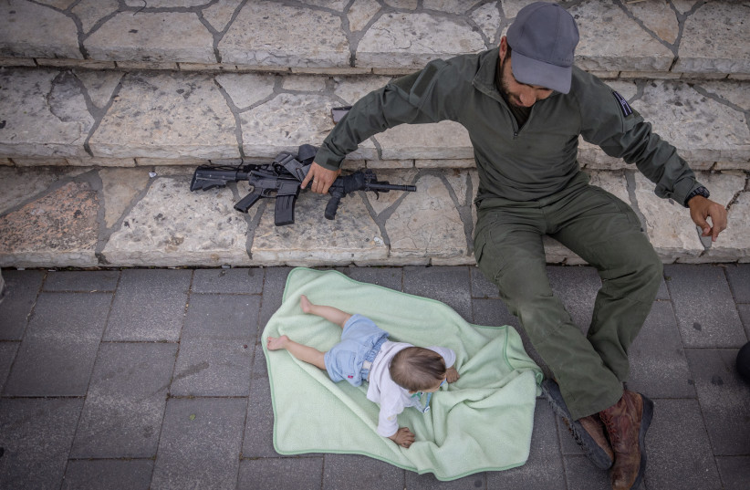  IDF RESERVIST with his toddler outside Jerusalem’s Mount Herzl, May 9. (credit: FLASH90)