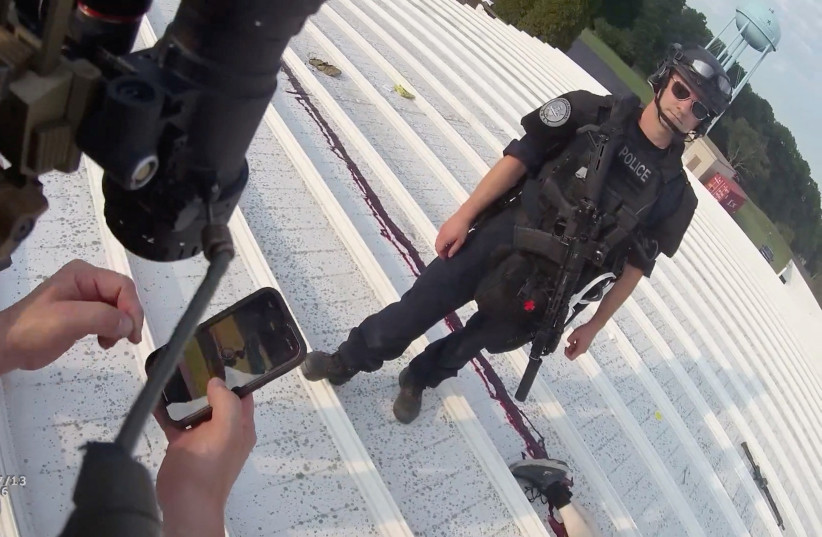 A police officer stands near the body of 20-year-old Thomas Crooks, who is identified as the gunman in the assassination attempt on former President Donald Trump during a campaign rally, in Butler, Pennsylvania, U.S., July 13, 2024 in this still image taken from bodycam video.