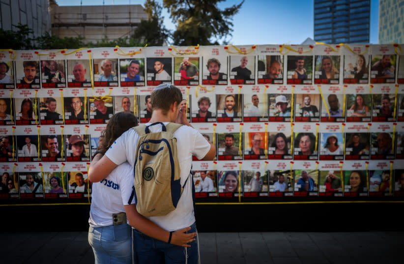 Varias personas observan fotografías de israelíes retenidos como rehenes por terroristas de Hamás en Gaza, en la Plaza de los Rehenes de Tel Aviv, el 5 de agosto de 2024.