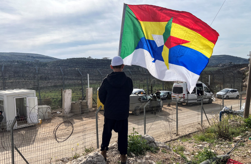 A Druze boy holds a flag as he looks at the ceasefire line between Golan Heights and Syria, on the day of first visit by Druze delegation from Syria just after 1973 war in Israel, March 14, 2025.