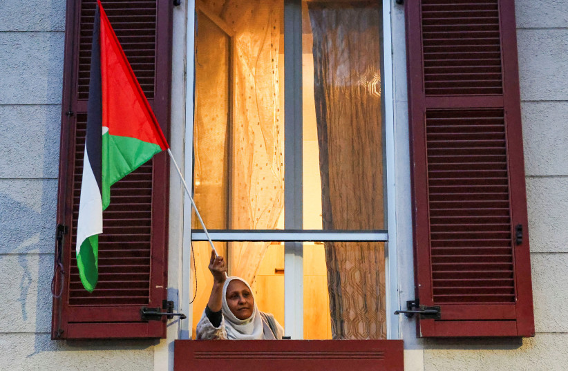A woman holds a Palestinian flag during a protest against the environmental, economic and social impact of the Milano-Cortina 2026 Winter Olympics in Milan, Italy, February 7, 2026.