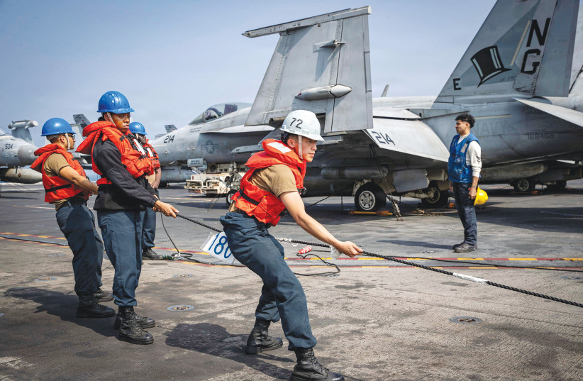 US Navy sailors heave a line on the flight deck of Nimitz-class aircraft carrier ‘USS Abraham Lincoln’ during a replenishment-at-sea in the Arabian Sea, Feb. 4.