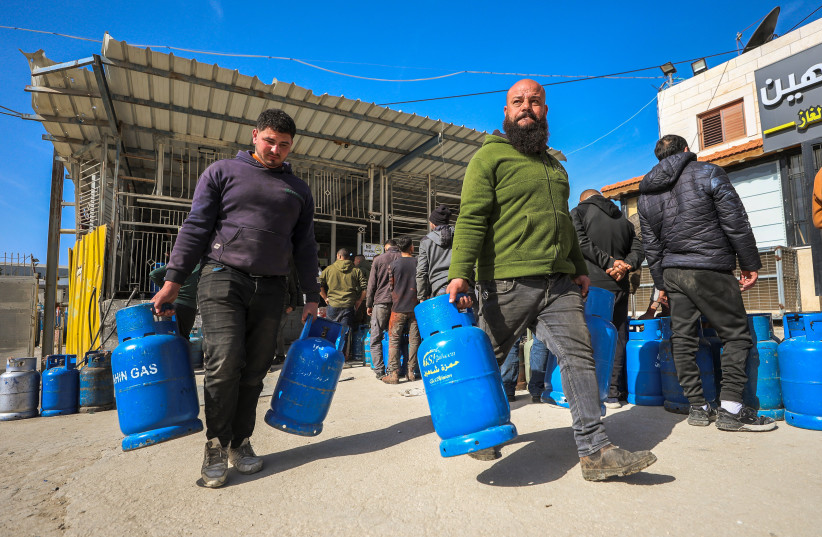 Palestinians carry gas cylinders at the Hamza Shaheen station in Hebron on January 24, 2026, amid a cooking gas shortage in the West Bank. Station owners report Israel has reduced gas supplies entering the territory since renewed threats of a US-Israeli-Iranian war.