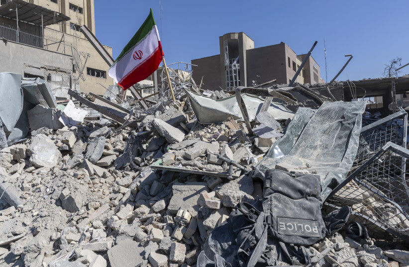 An Iranian flag is planted in the rubble of a police station, damaged in airstrikes yesterday, on March 3, 2026 in Tehran, Iran.