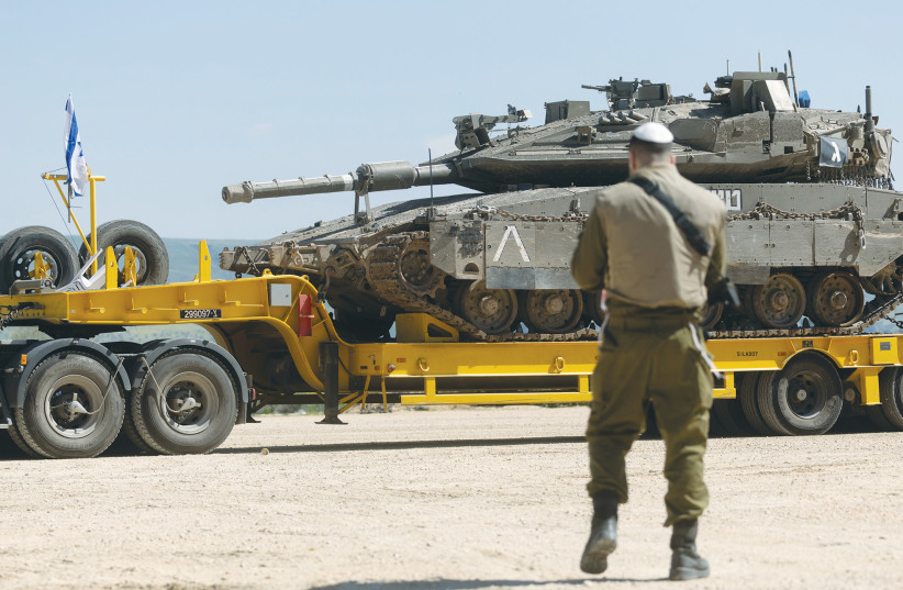 AN IDF soldier stands near a truck carrying an Israeli tank near the border with Lebanon, last week.