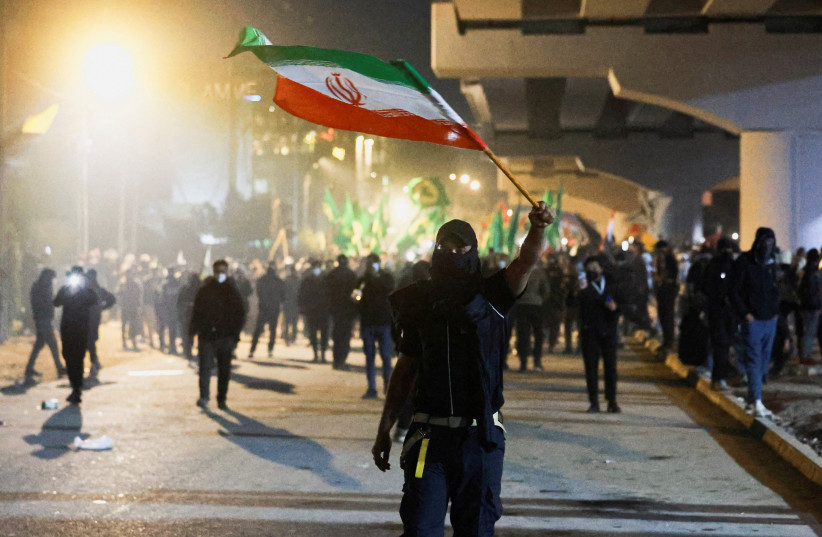A protester holds an Iranian flag as supporters of Iraqi Shi'ite armed groups attempt to move toward the US embassy located in Baghdad's Green Zone, Iraq, March 1, 2026.