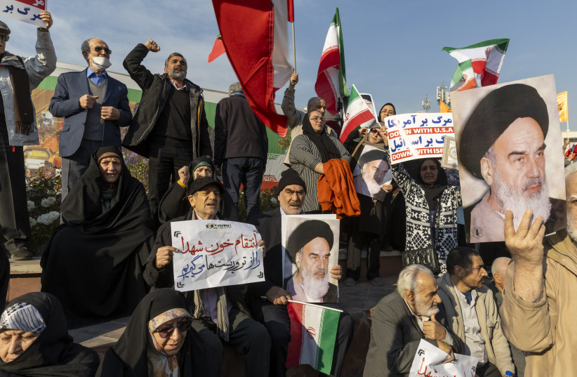 People hold placards and wave flags during a pro-government demonstration on January 12, 2026 in Tehran, Iran.