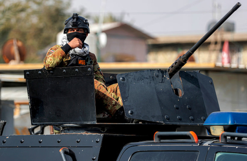 A member of the Iraqi security forces mans a turret while on guard during a funerary procession for a slain member of Iraq's Hashed al-Shaabi, or the Popular Mobilisation Forces (PMF) in Baghdad on March 8, 2026.