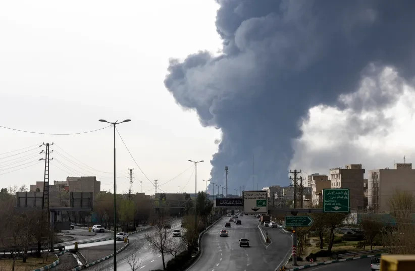 Los coches circulan por una autopista mientras el humo se eleva tras los ataques aéreos nocturnos contra depósitos de petróleo el 8 de marzo de 2026 en Teherán, Irán. (credit: Majid Saeedi/Getty Images)