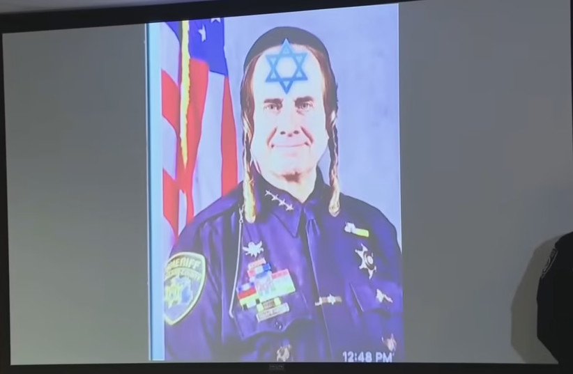 An antisemitic meme featuring Bouchard is projected during a press conference on March 19, 2026.