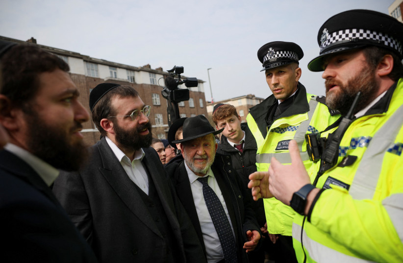Local community members talk with police officers from London's Metropolitan Police following a suspected antisemitic arson attack in Golders Green, London, March 23, 2026.