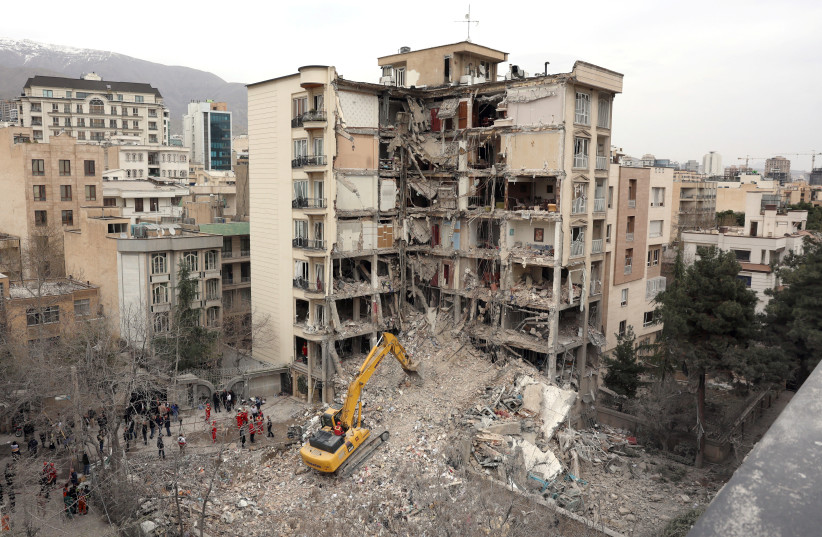 An excavator clears rubble from destroyed buildings in northern Tehran on March 23, 2026.