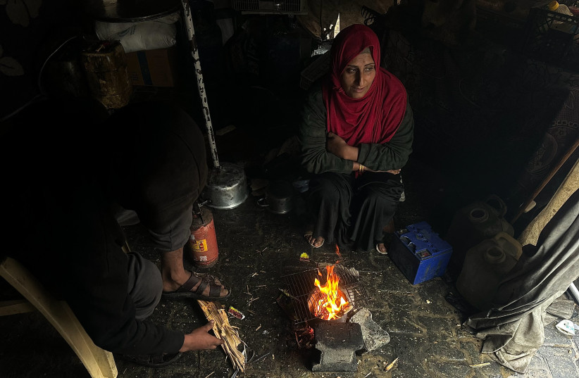 A displaced Palestinian family gathers around a fire inside a tent following heavy rain in Khan Yunis, in the southern Gaza Strip, last month.