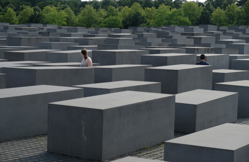 People walk amid concrete slabs or ''stelae'' in The Memorial to the Murdered Jews of Europe, also known as the Holocaust Memorial designed by architect Peter Eisenman and engineer Buro Happold seen on July 14, 2017 in Berlin, Germany.