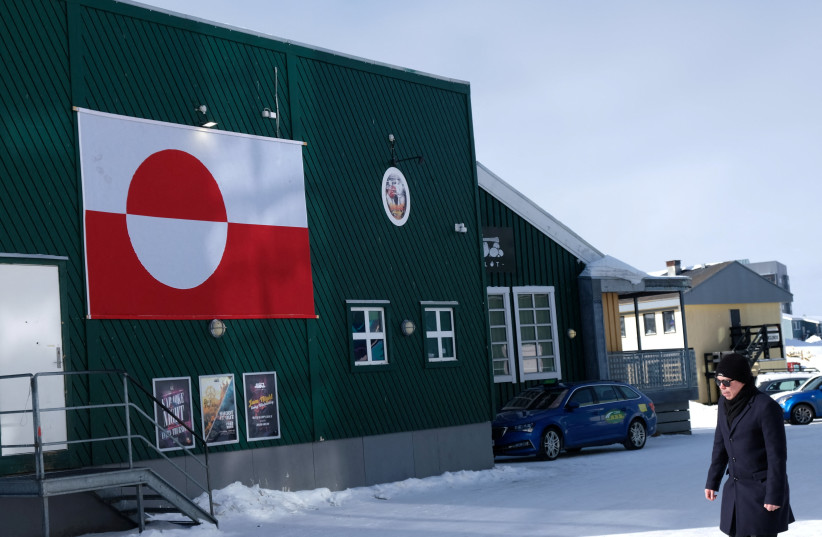 A person walks next to a Greenlandic flag on a house in Nuuk, Greenland, March 17, 2026.