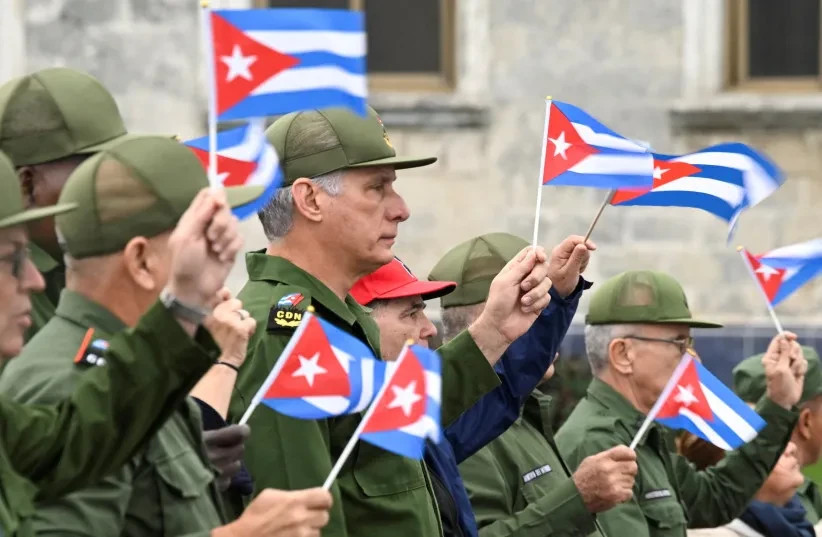 El presidente de Cuba, Miguel Díaz-Canel, ondea una bandera cubana junto a otras personas durante una marcha frente a la embajada de Estados Unidos para protestar contra lo que denuncian como agresión estadounidense en la región, tras la captura del líder venezolano Nicolás Maduro
