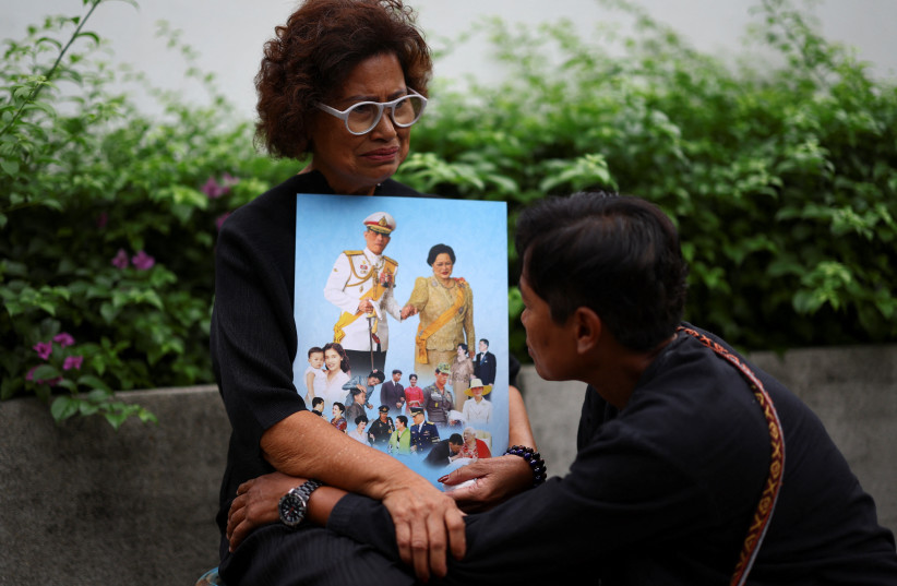 People react while holding a picture of Thai King Maha Vajiralongkorn and Thailand's Queen Mother Sirikit, 93, following the announcement of her death, outside King Chulalongkorn Memorial Hospital in Bangkok, Thailand, October 25, 2025.