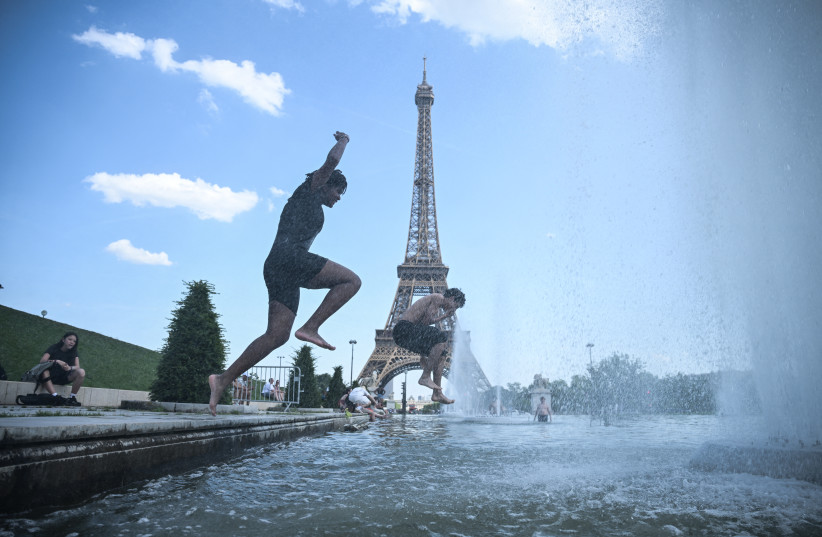 TOPSHOT-FRANCE-WEATHER-CLIMATE-HEAT TOPSHOT - People jump in the Trocadero Fountain near the Eiffel Tower during a heatwave in Paris on June 22, 2026.